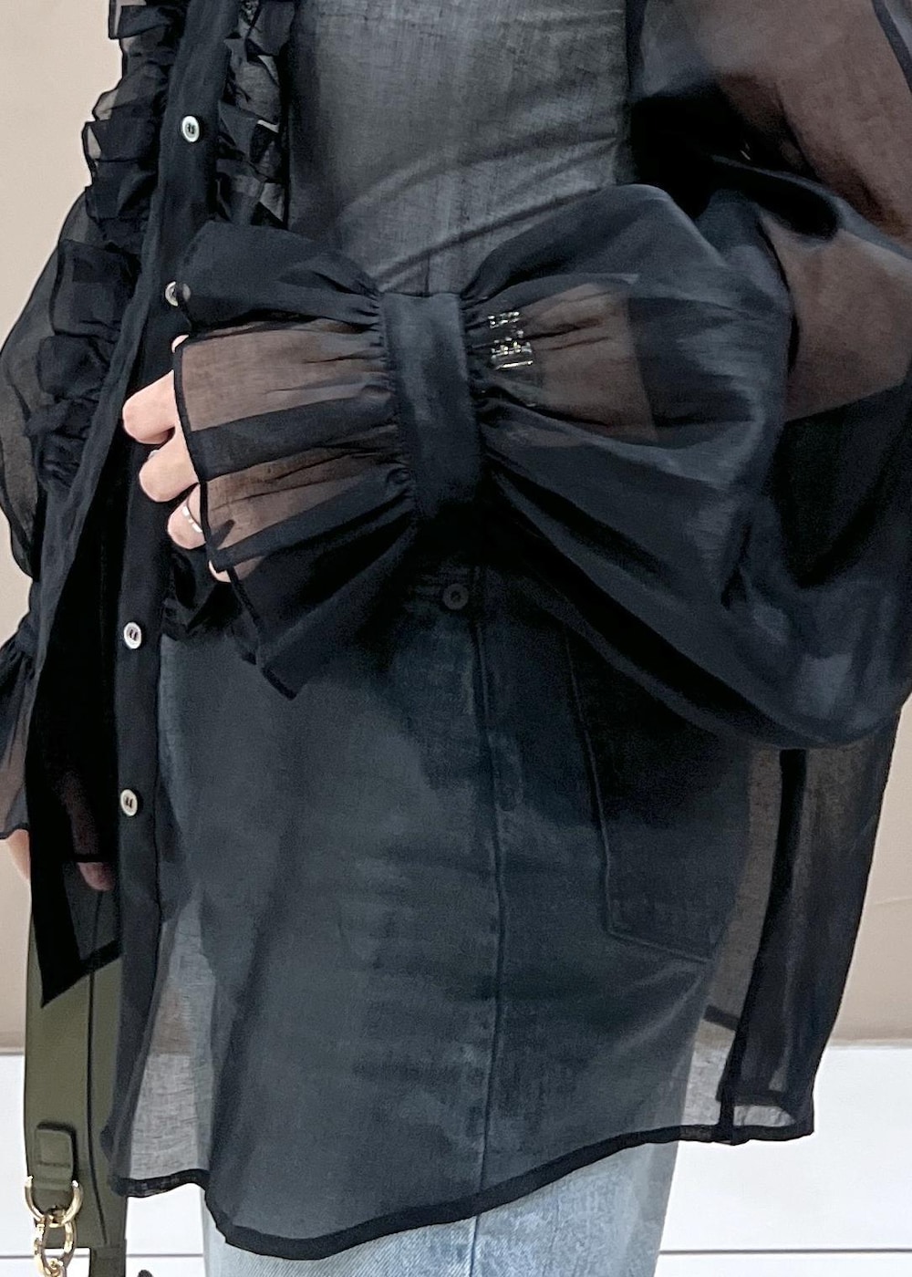 グリーン系のショルダーバッグ、ブルー系のデニムパンツ、ホワイト系のスニーカーを着用したレディースの夏コーディネートの5枚目の写真