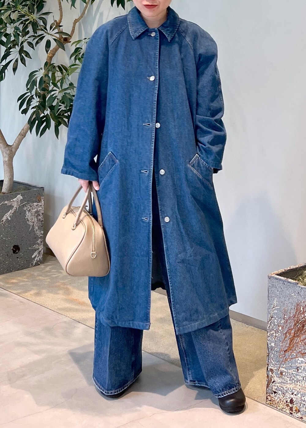 ベージュ系のボストンバッグ、ブルー系のデニムパンツ、ホワイト系のベストを着用したレディースの冬コーディネートの8枚目の写真