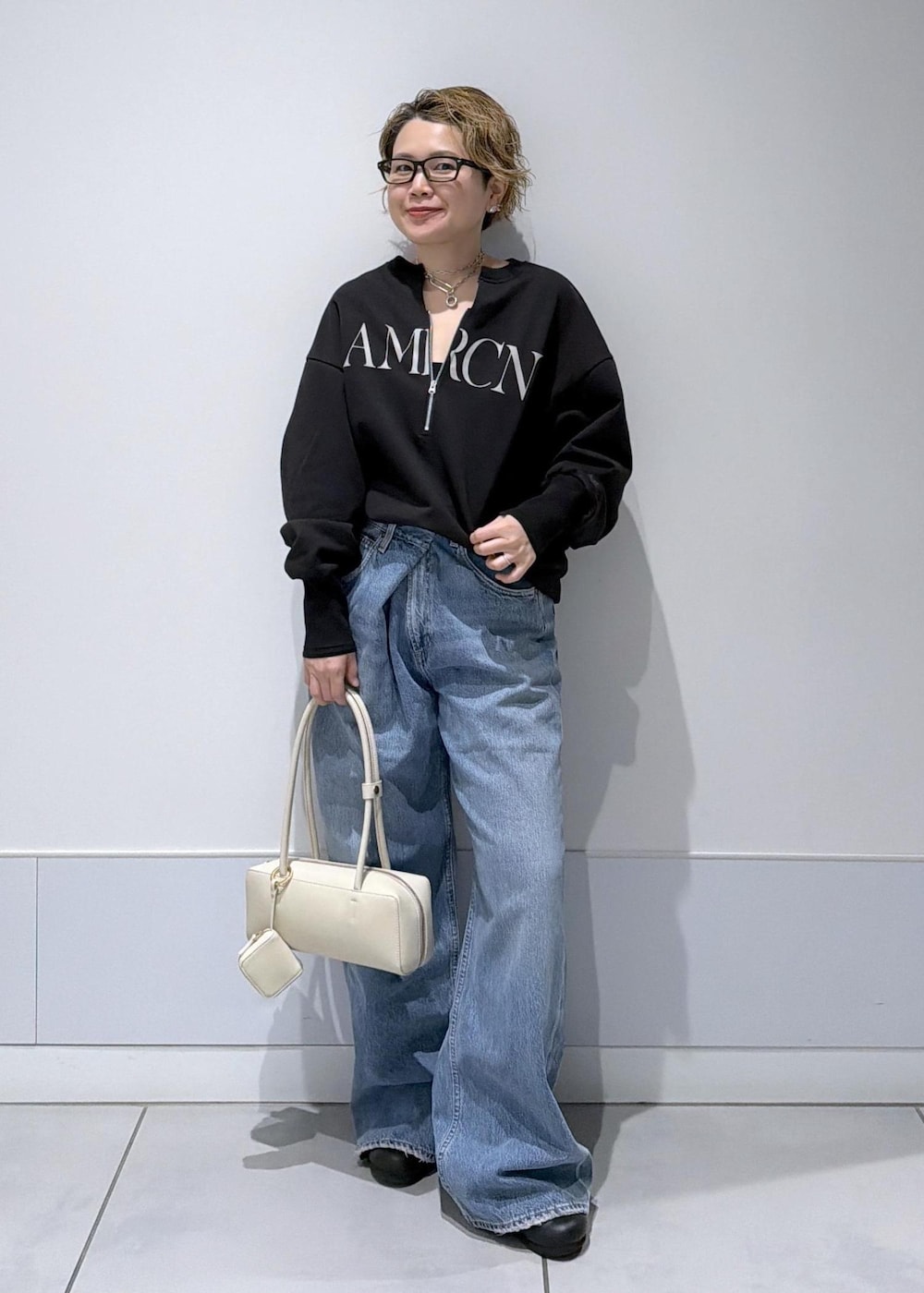 ブラック系のスウェット、ブルー系のデニムパンツを着用したレディースの冬コーディネートの4枚目の写真