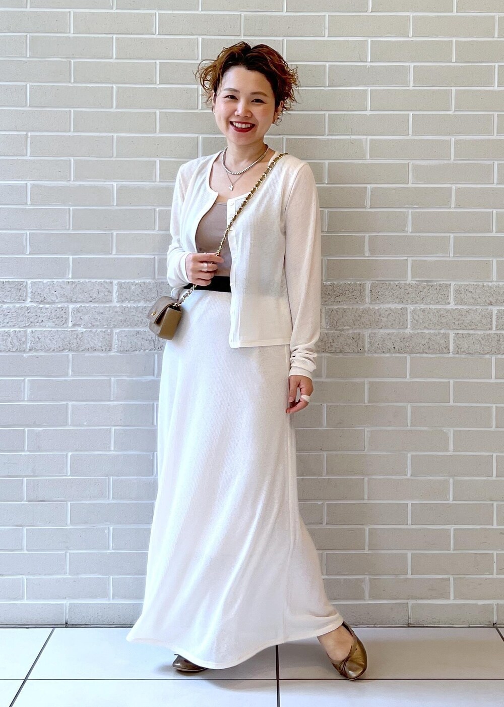 ホワイト系のスカート、ベージュ系のショルダーバッグ、ホワイト系のカーディガン/ボレロを着用したレディースの夏コーディネートの3枚目の写真