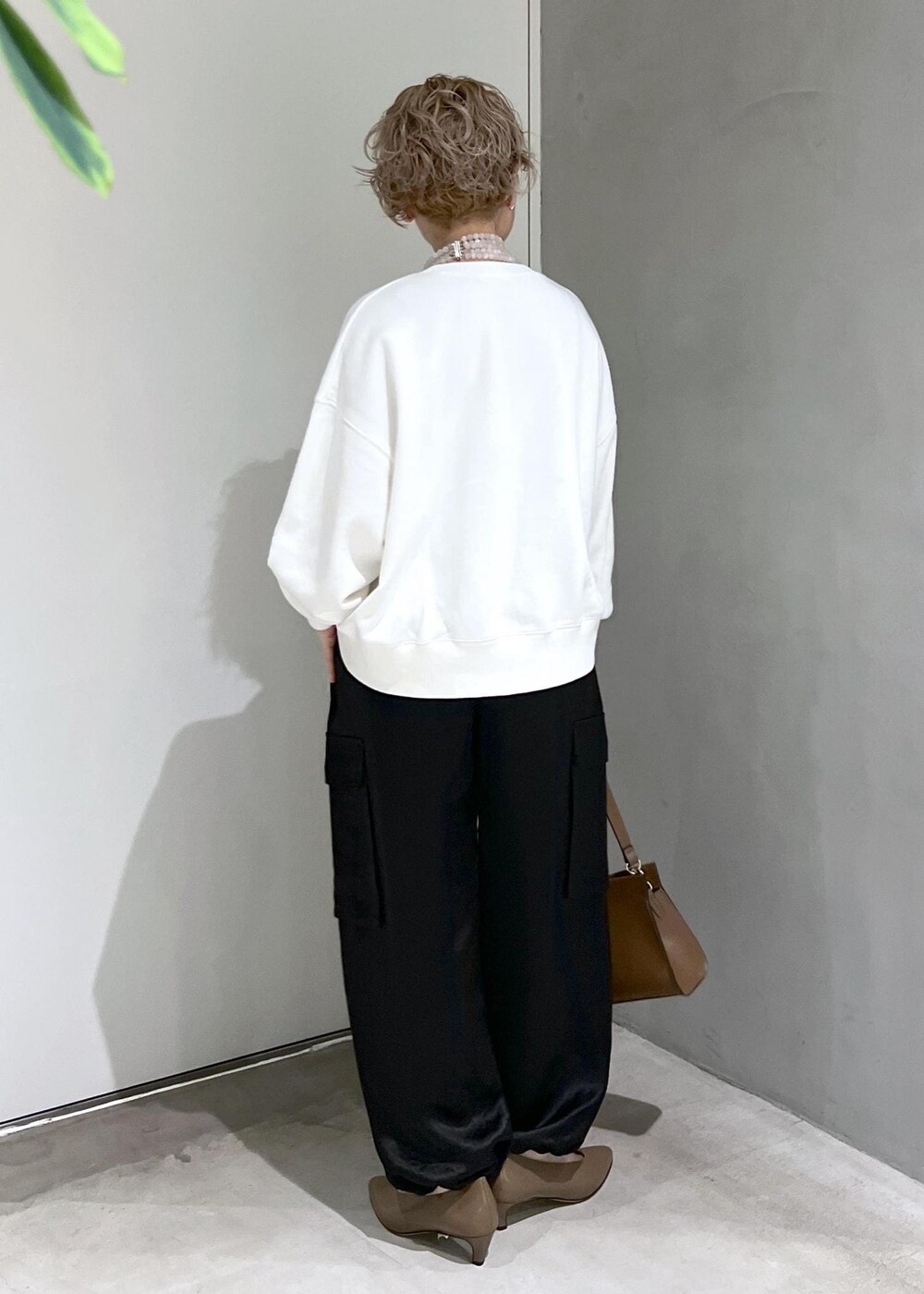 ホワイト系のスウェット、ブラック系のカーゴパンツ、ブラウン系のショルダーバッグを着用したレディースの秋コーディネートの6枚目の写真