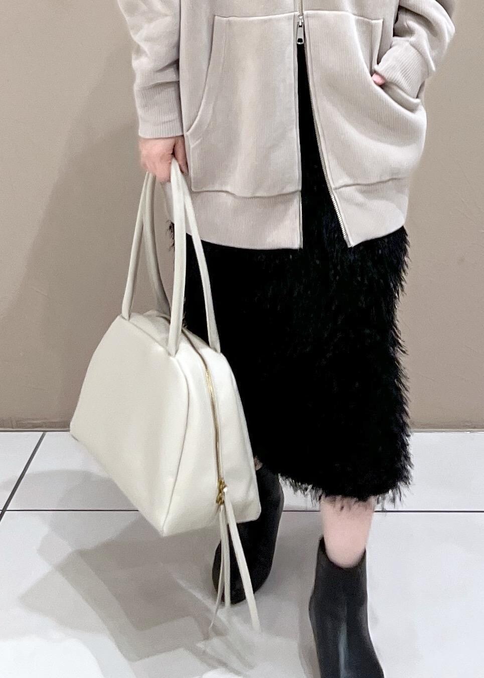 ベージュ系のパーカー、ホワイト系のボストンバッグ、ブラック系のブーツを着用したレディースの秋コーディネートの7枚目の写真