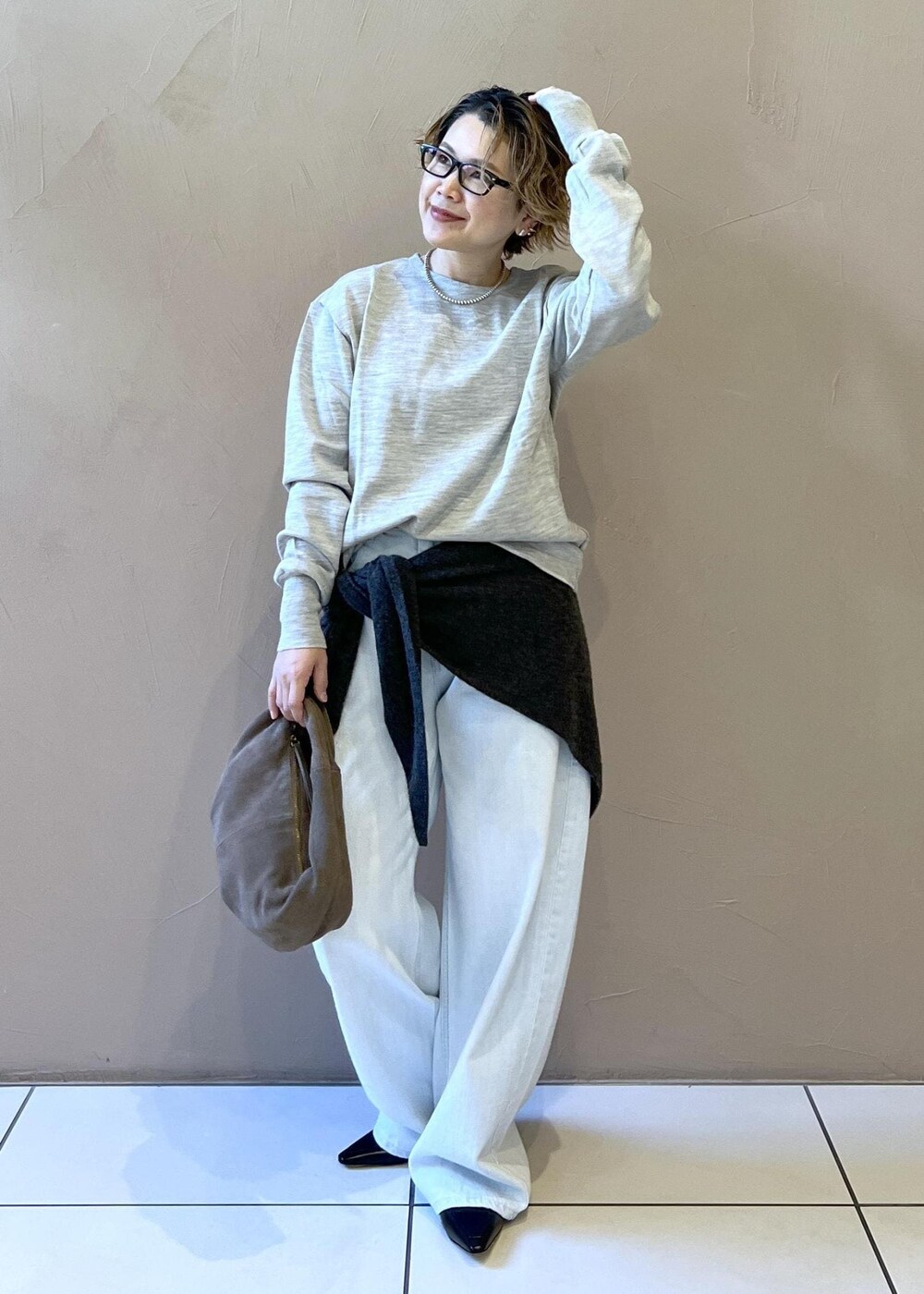 ブルー系のデニムパンツ、グレー系のハンドバッグ、ブラック系のパンプスを着用したレディースの秋コーディネートの3枚目の写真