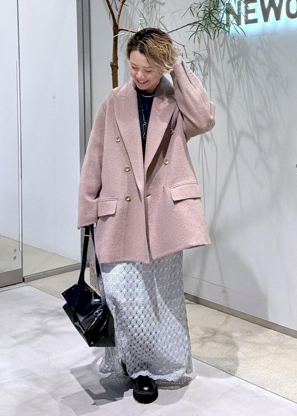 ブラック系のショルダーバッグ、グリーン系のスカート、ブラウン系のチェスターコートを着用したレディースの秋コーディネートの2枚目の写真