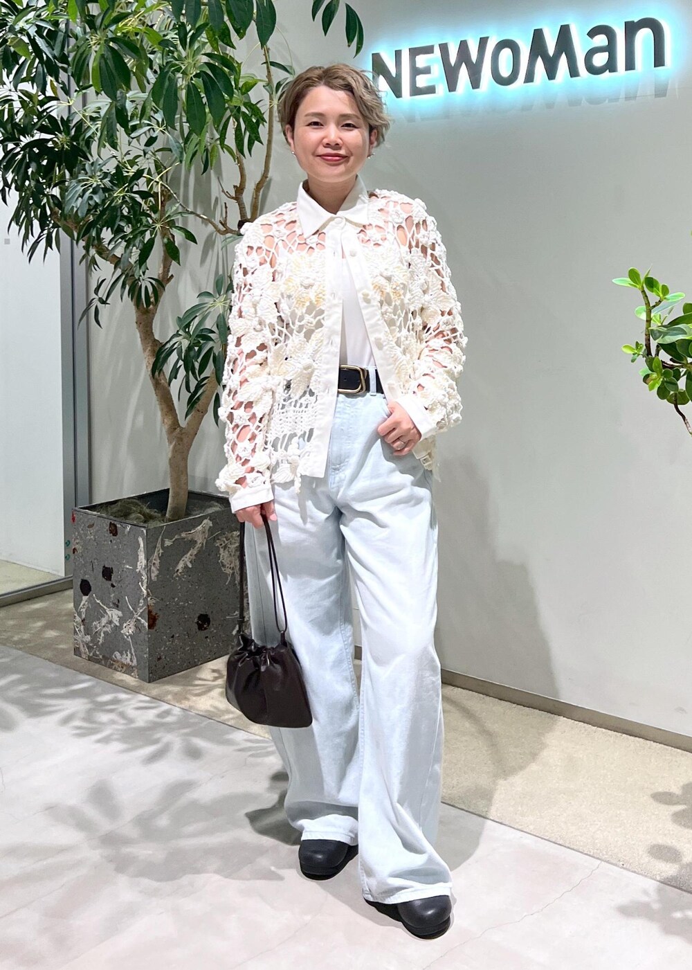 ブルー系のデニムパンツ、ブラウン系のハンドバッグを着用したレディースの夏コーディネートの5枚目の写真