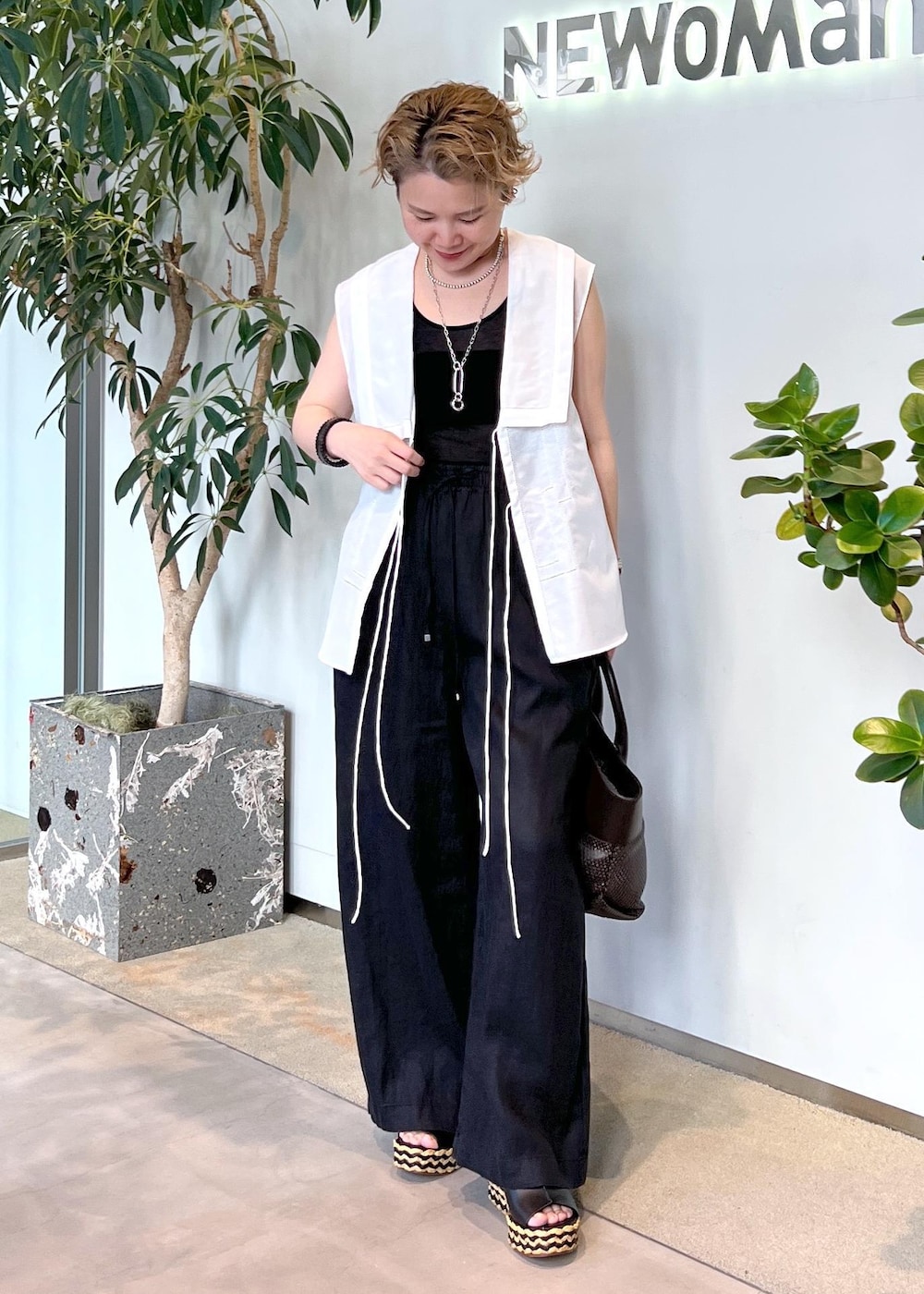 ブラック系のその他パンツ、ブラウン系のトートバッグ、ホワイト系のシャツ/ブラウスを着用したレディースの夏コーディネートの4枚目の写真