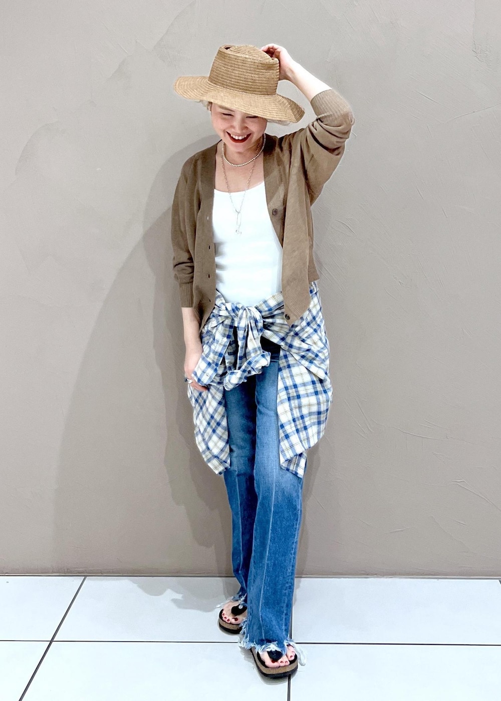 ホワイト系のタンクトップ、ゴールド系のカーディガン/ボレロ、ブルー系のデニムパンツを着用したレディースの夏コーディネートの9枚目の写真