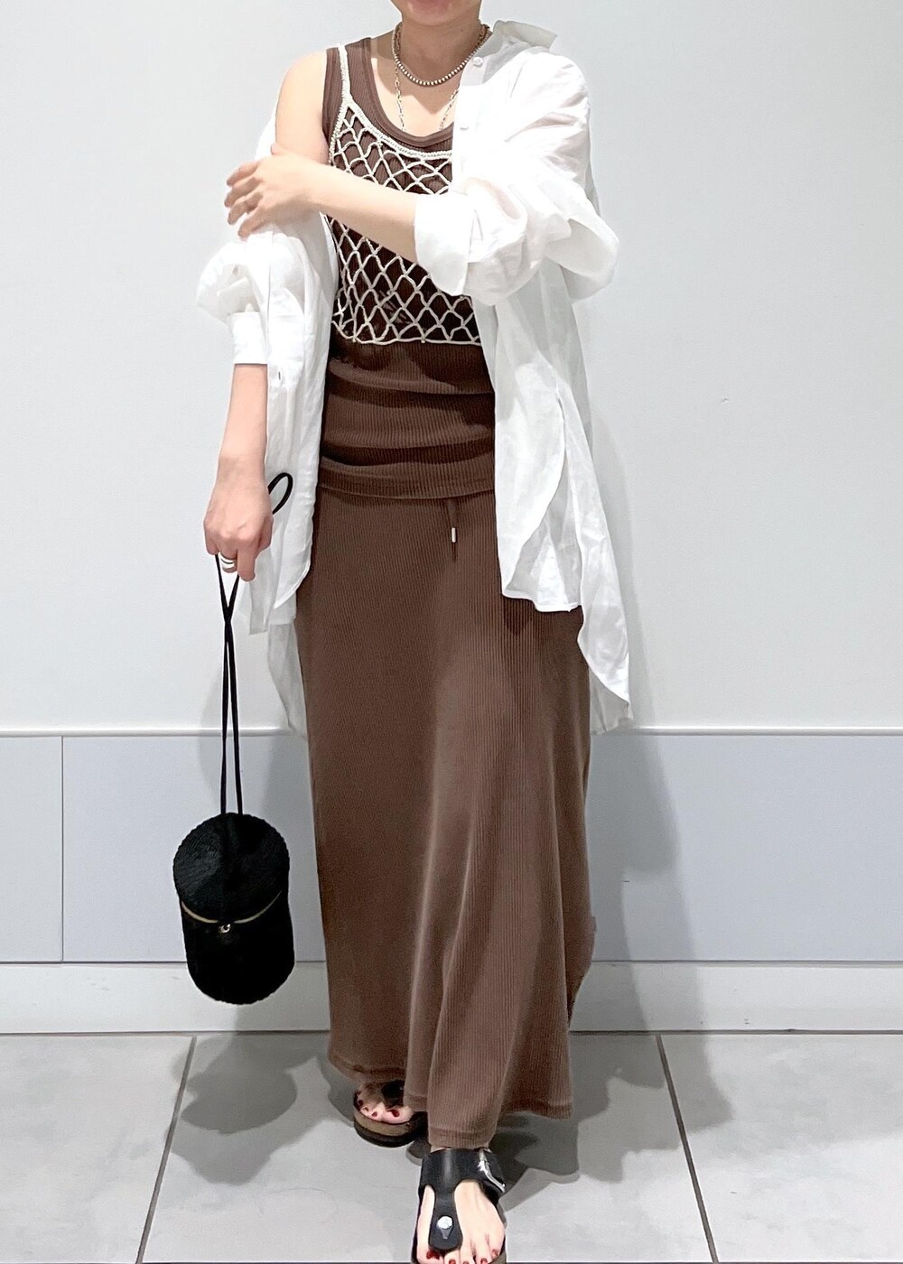 ブラック系のショルダーバッグ、ベージュ系のキャミソール、ブラウン系のタンクトップを着用したレディースの夏コーディネートの5枚目の写真