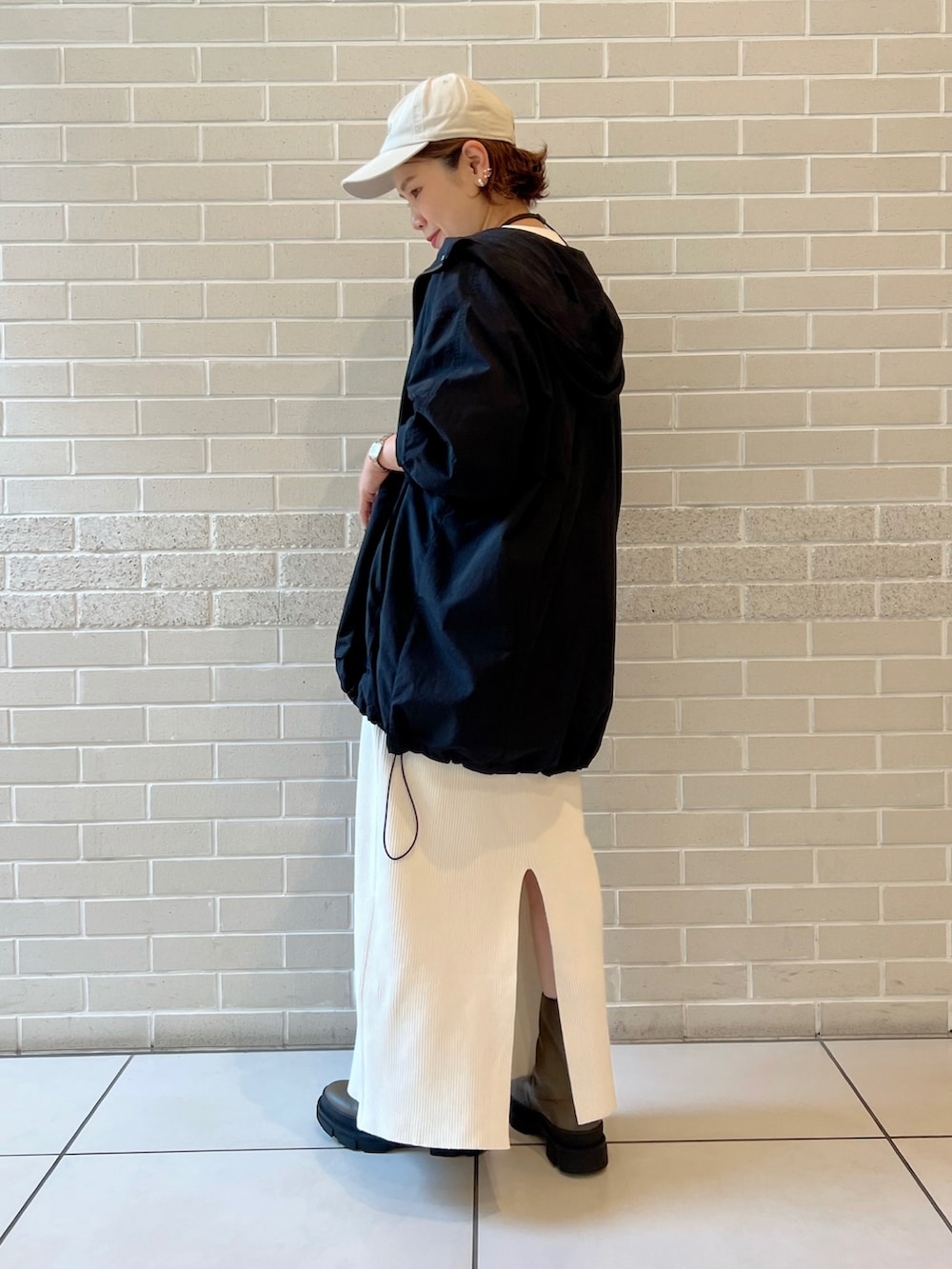 ホワイト系のTシャツ/カットソー、ブラック系のマウンテンパーカー、ホワイト系のスカートを着用したレディースの秋コーディネートの3枚目の写真