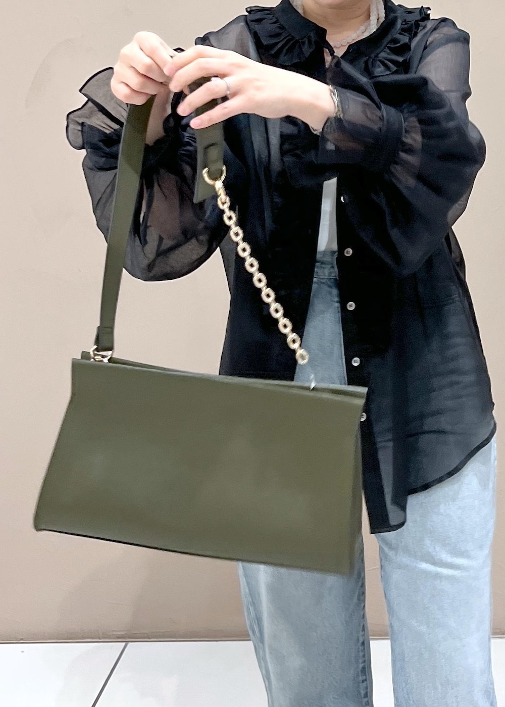 グリーン系のショルダーバッグ、ブルー系のデニムパンツ、ホワイト系のスニーカーを着用したレディースの夏コーディネートの7枚目の写真