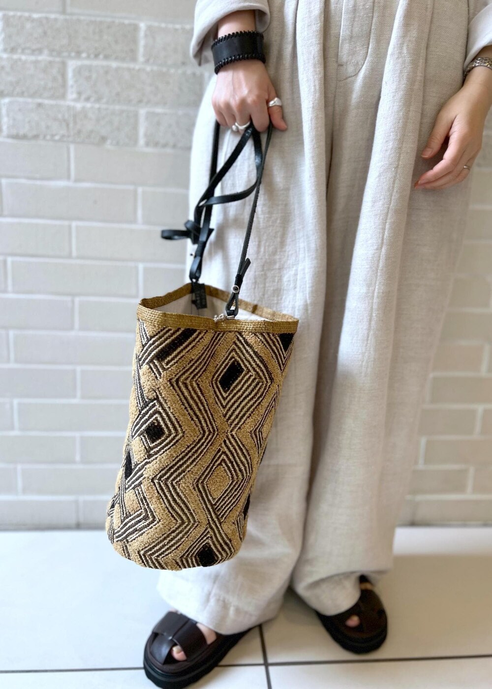 ブラウン系のサンダル、ホワイト系のカーディガン/ボレロ、ホワイト系のスラックスを着用したレディースの夏コーディネートの7枚目の写真