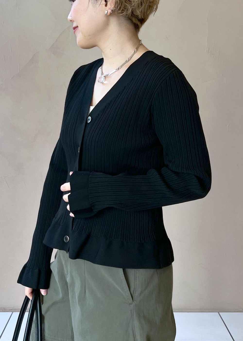 ブラック系のカーディガン/ボレロ、グリーン系のその他パンツ、ブラック系のボストンバッグを着用したレディースの冬コーディネートの6枚目の写真