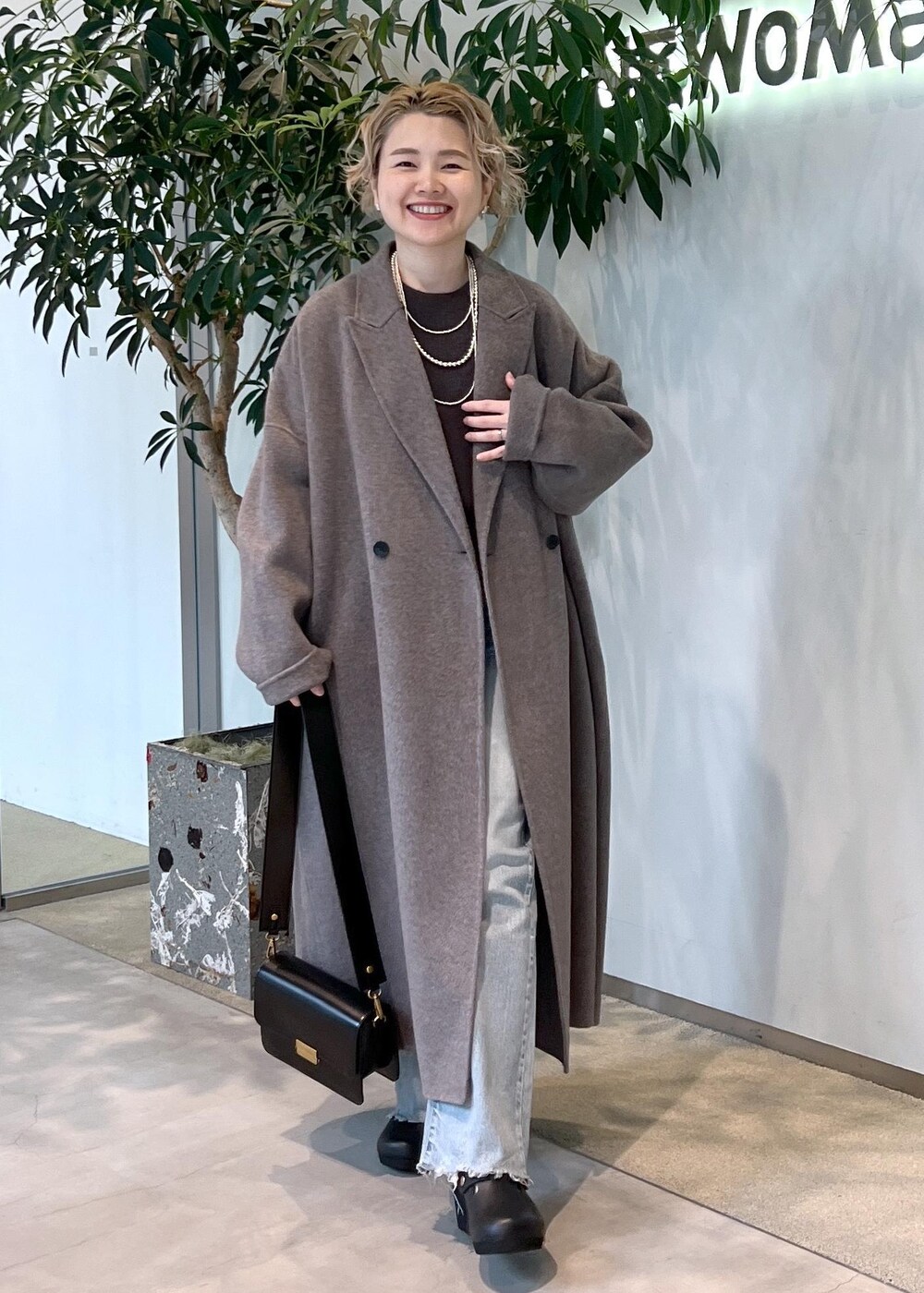 グレー系のニット/セーター、ブラック系のショルダーバッグ、ブラウン系のその他アウターを着用したレディースの秋コーディネートの2枚目の写真