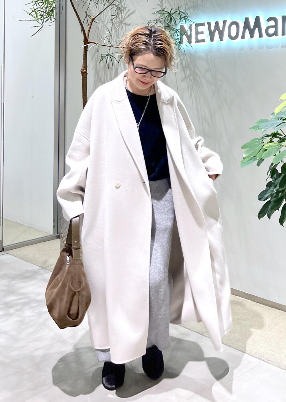 ホワイト系のチェスターコート、ブラック系のスウェット、ブラウン系のショルダーバッグを着用したレディースの秋コーディネートの3枚目の写真