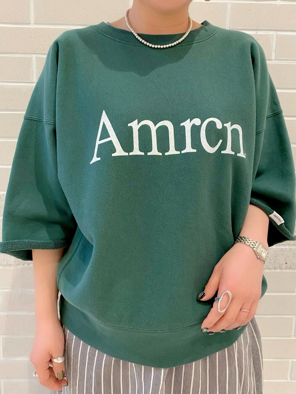 グリーン系のスウェット、ブラック系のワンピース、ブラウン系のサンダルを着用したレディースの春コーディネートの2枚目の写真