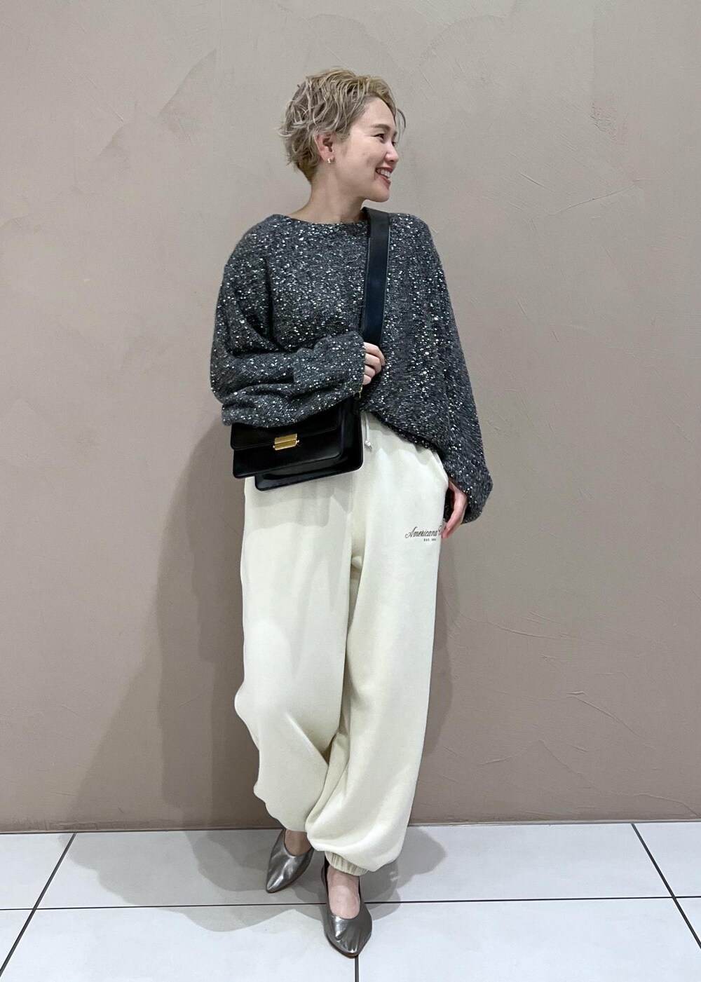 ホワイト系のスウェットパンツ、ブラック系のショルダーバッグ、シルバー系のパンプスを着用したレディースの秋コーディネートの3枚目の写真