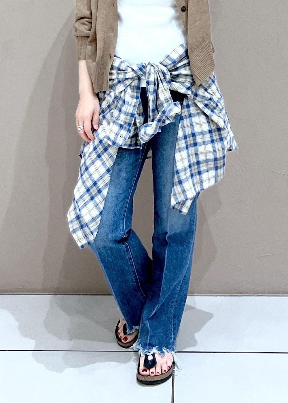 ホワイト系のタンクトップ、ゴールド系のカーディガン/ボレロ、ブルー系のデニムパンツを着用したレディースの夏コーディネートの4枚目の写真