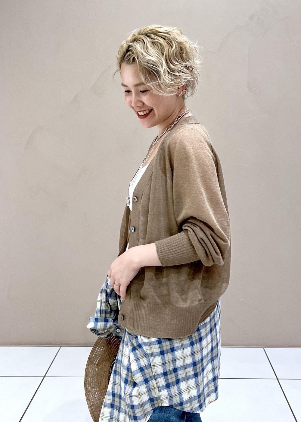 ホワイト系のタンクトップ、ゴールド系のカーディガン/ボレロ、ブルー系のデニムパンツを着用したレディースの夏コーディネートの5枚目の写真