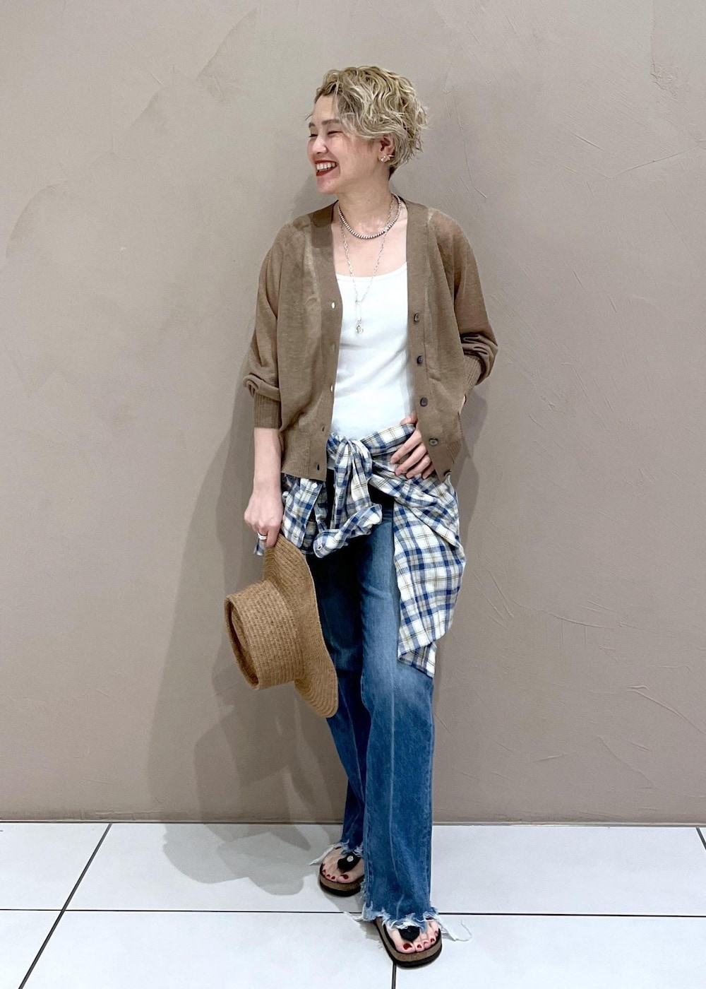 ホワイト系のタンクトップ、ゴールド系のカーディガン/ボレロ、ブルー系のデニムパンツを着用したレディースの夏コーディネートの2枚目の写真