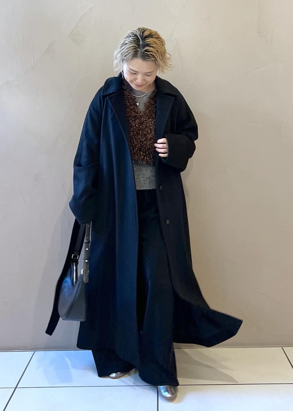 ブラック系のベスト、グレー系のニット/セーター、ブラック系のステンカラーコートを着用したレディースの冬コーディネートの4枚目の写真