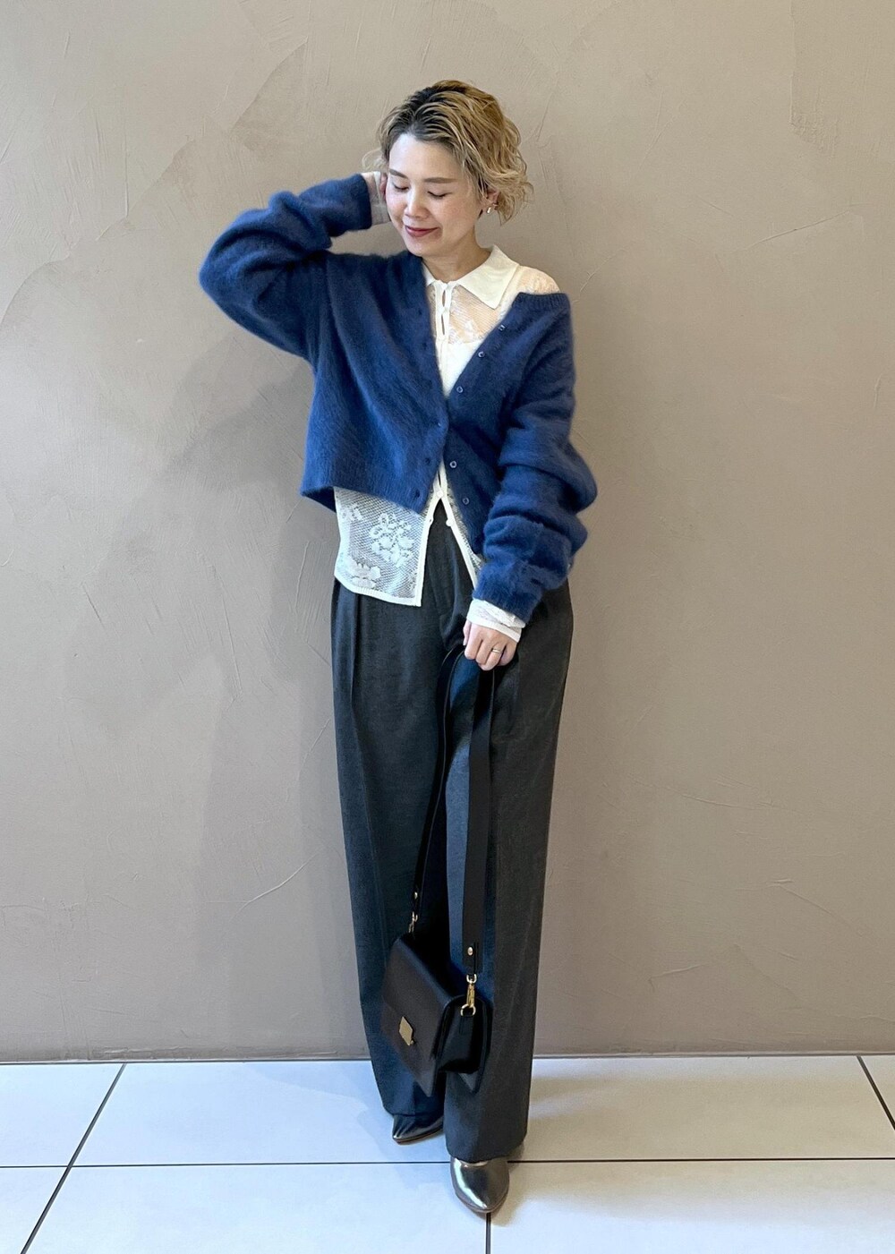 ブラック系のショルダーバッグ、ブルー系のカーディガン/ボレロ、グレー系のスラックスを着用したレディースの冬コーディネートの4枚目の写真