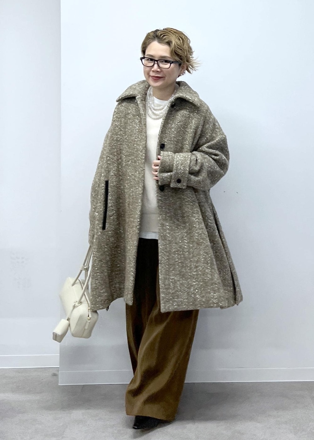 ホワイト系のスウェット、ベージュ系のステンカラーコート、ブラウン系のその他パンツを着用したレディースの秋コーディネートの2枚目の写真