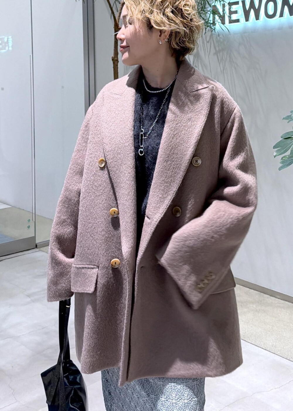 ブラック系のショルダーバッグ、グリーン系のスカート、ブラウン系のチェスターコートを着用したレディースの秋コーディネートの7枚目の写真