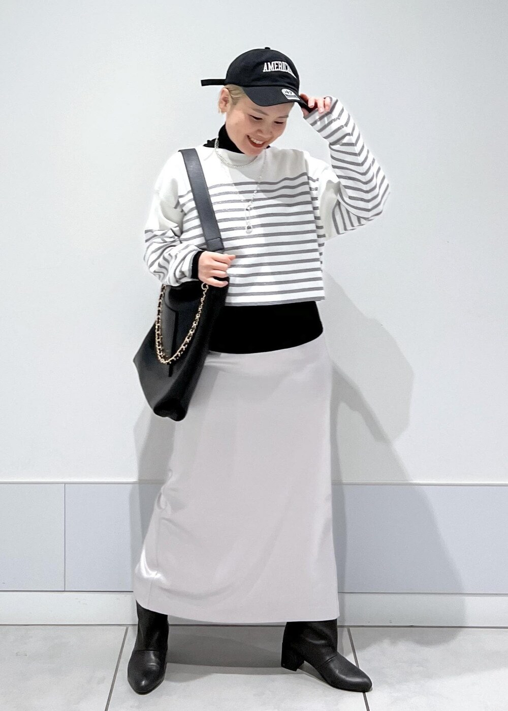 ブラック系のブーツ、ブラック系のTシャツ/カットソー、シルバー系のスカートを着用したレディースの冬コーディネートの4枚目の写真