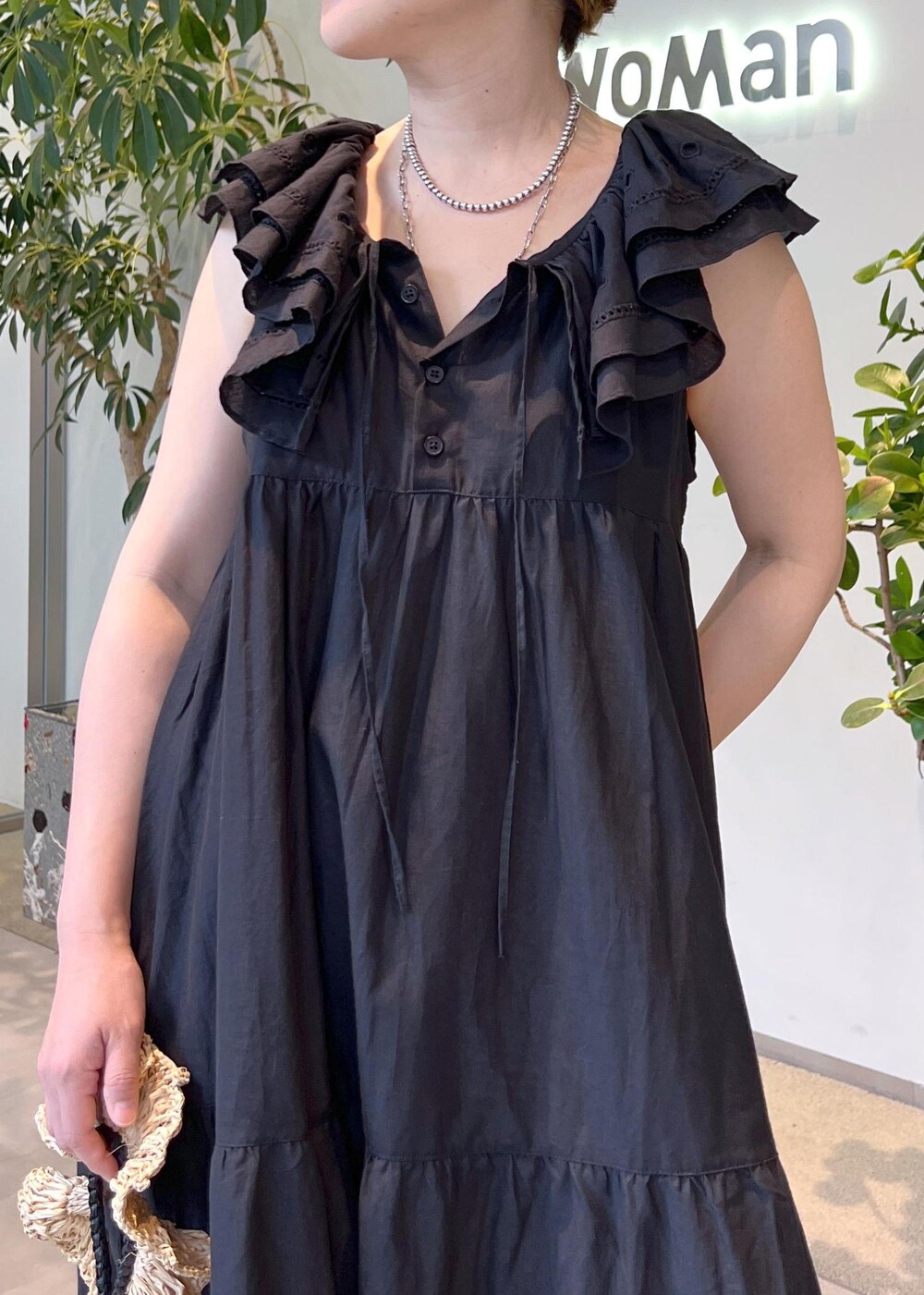 ブラック系のワンピース、ホワイト系のハンドバッグ、ブラック系のサンダルを着用したレディースの夏コーディネートの7枚目の写真