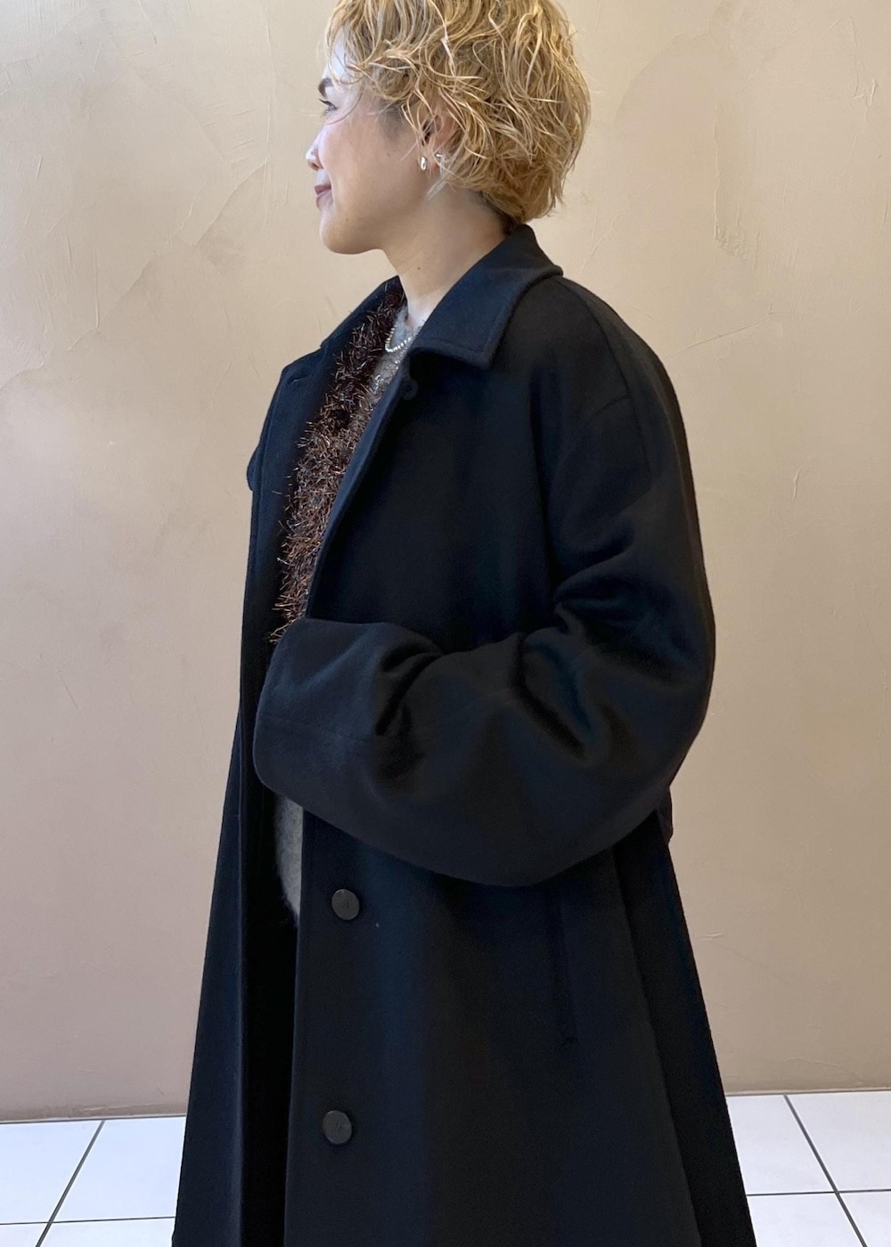 ブラック系のベスト、グレー系のニット/セーター、ブラック系のステンカラーコートを着用したレディースの冬コーディネートの7枚目の写真