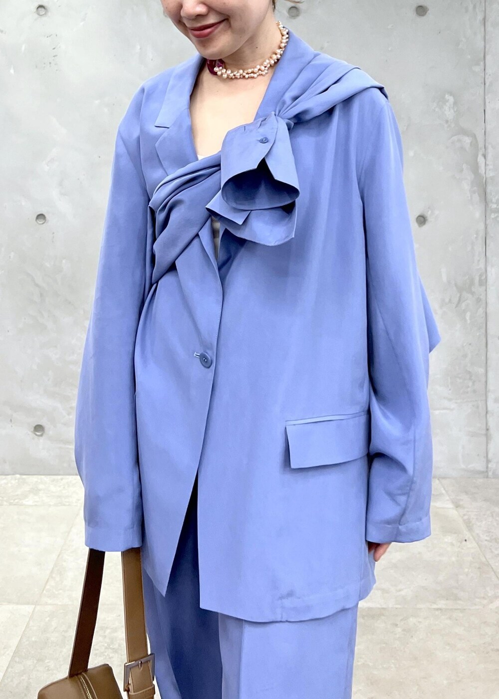 ブラウン系のショルダーバッグ、ブラウン系のサンダル、ブルー系のテーラードジャケットを着用したレディースの冬コーディネートの6枚目の写真