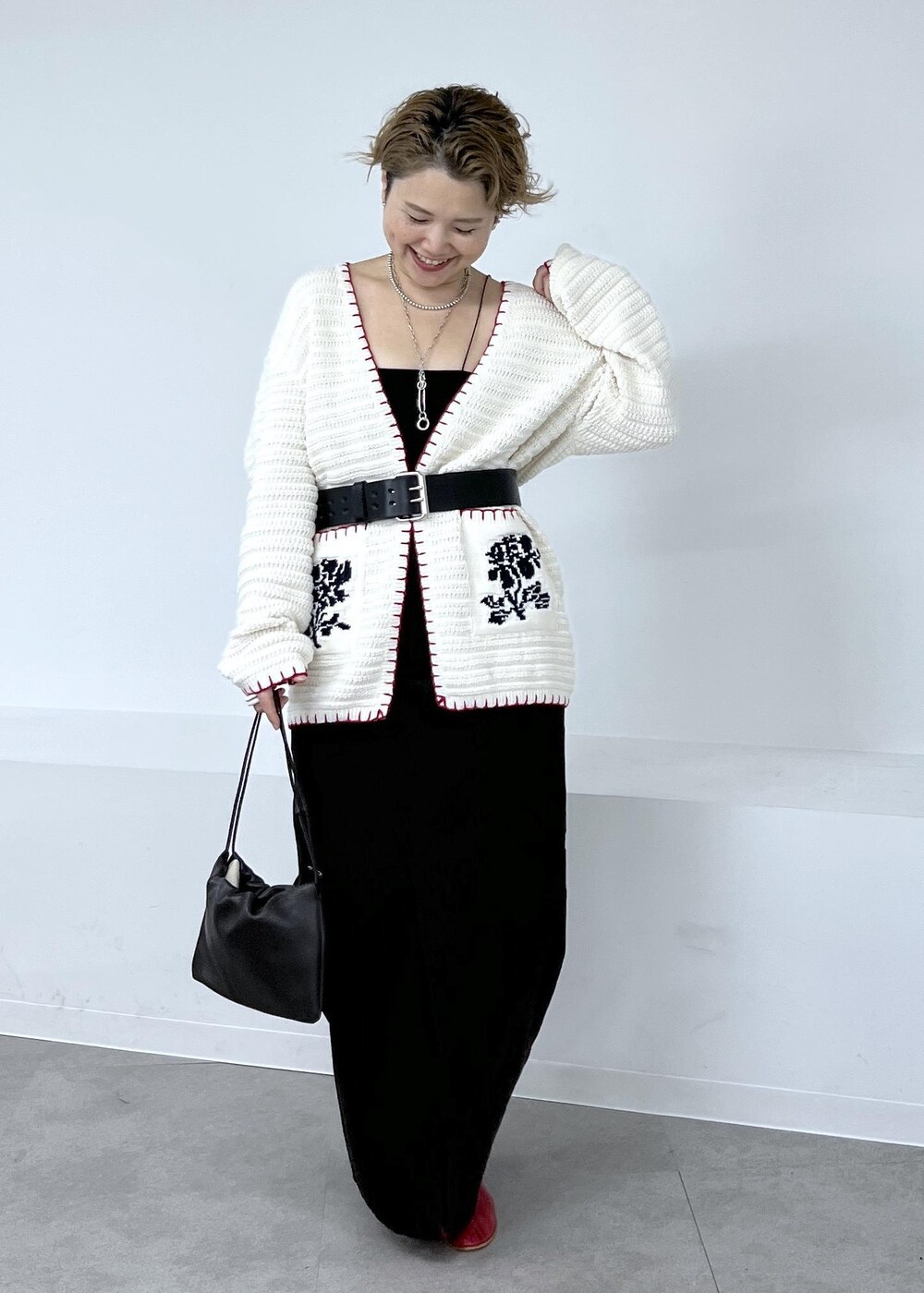 グレー系のスカート、ホワイト系のニット/セーター、レッド系のブーツを着用したレディースの秋コーディネートの2枚目の写真