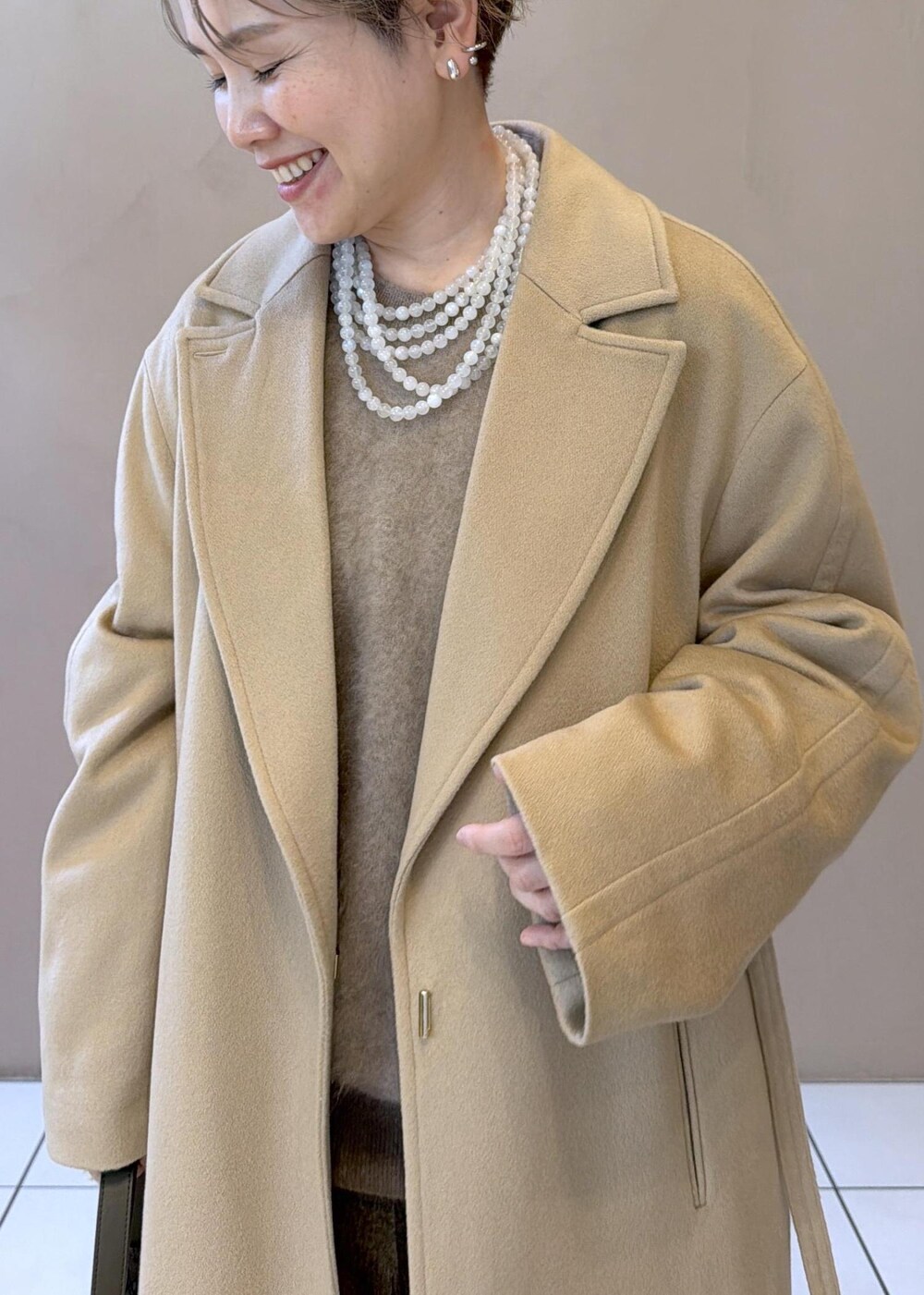 イエロー系のトレンチコート、ゴールド系のその他パンツ、ベージュ系のニット/セーターを着用したレディースの冬コーディネートの9枚目の写真