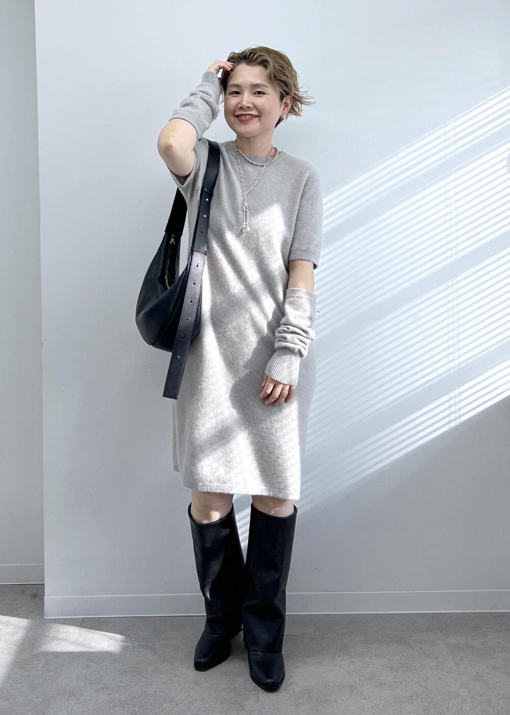 ブラック系のショルダーバッグ、ブラック系のブーツ、ベージュ系のワンピースを着用したレディースの秋コーディネートの2枚目の写真