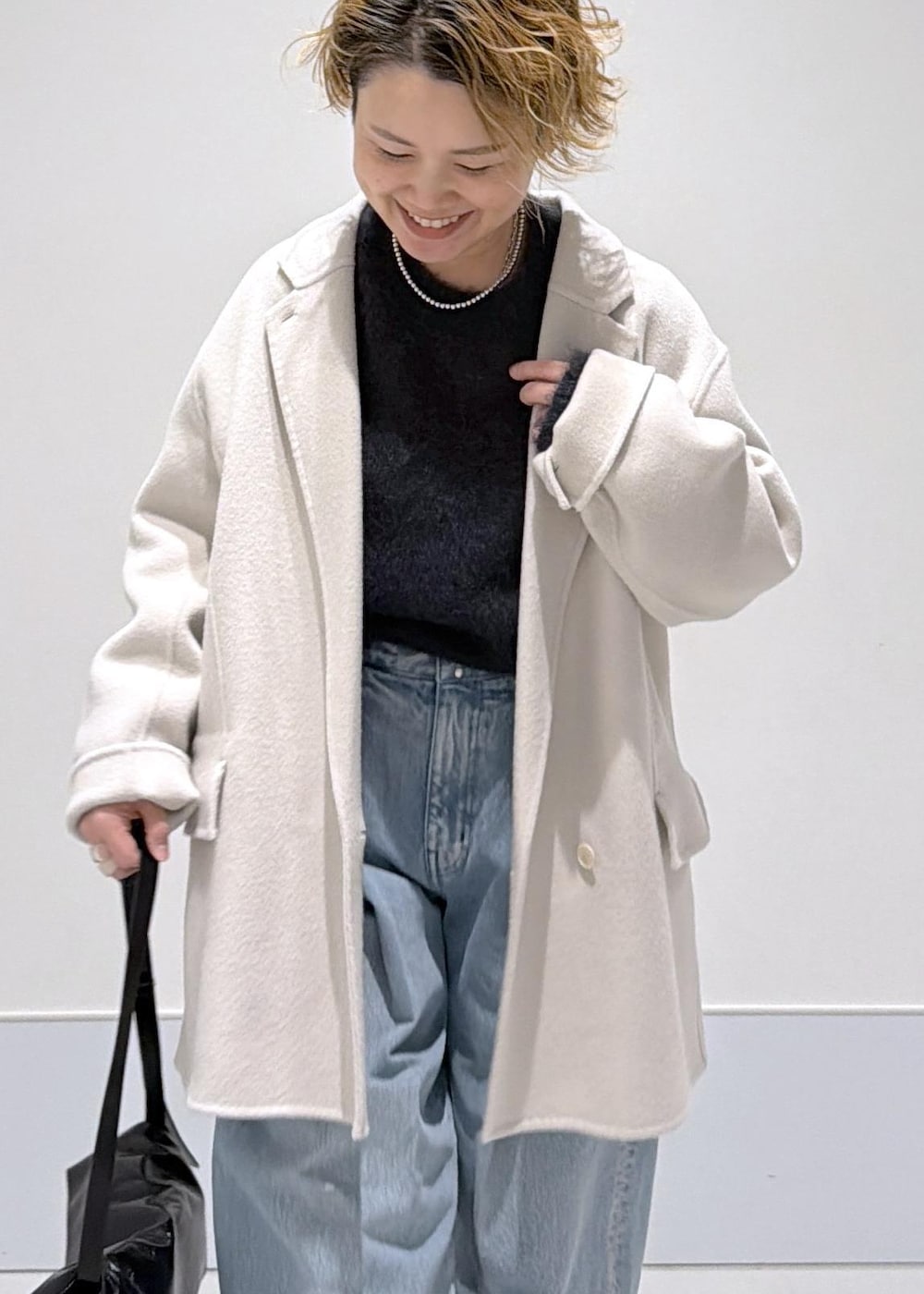 ブラック系のショルダーバッグ、ホワイト系のその他アウター、ブラック系のブーツを着用したレディースの秋コーディネートの5枚目の写真