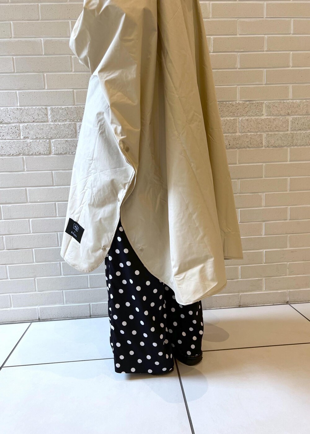 ベージュ系のトートバッグ、ブラック系のつなぎ/オールインワン、ベージュ系のレインコート/ポンチョを着用したレディースの夏コーディネートの9枚目の写真