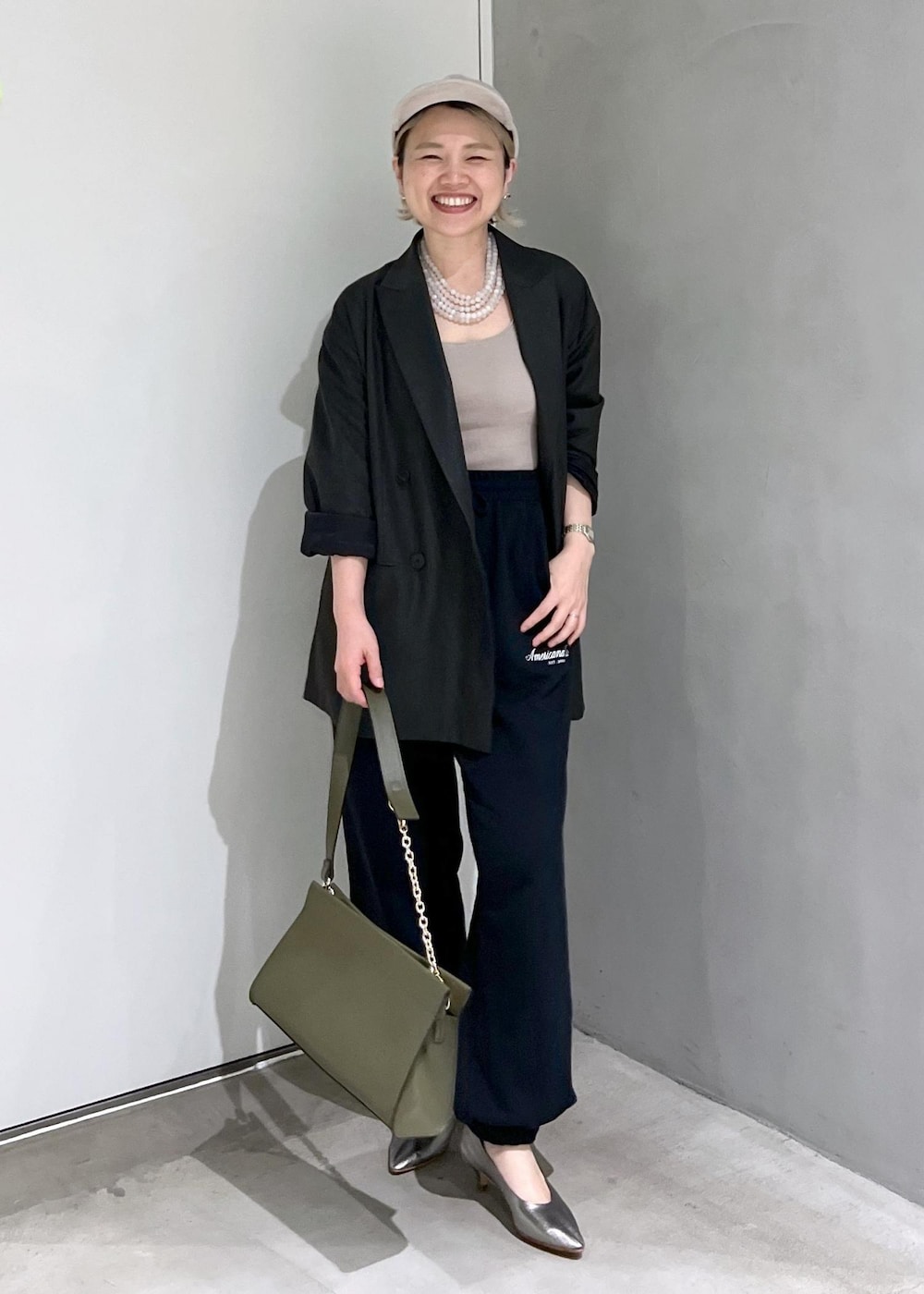 グリーン系のショルダーバッグ、ブラック系のスウェットパンツ、シルバー系のパンプスを着用したレディースの秋コーディネートの2枚目の写真