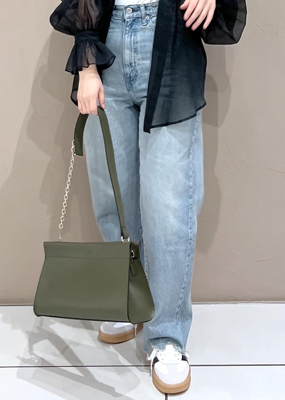 グリーン系のショルダーバッグ、ブルー系のデニムパンツ、ホワイト系のスニーカーを着用したレディースの夏コーディネートの9枚目の写真