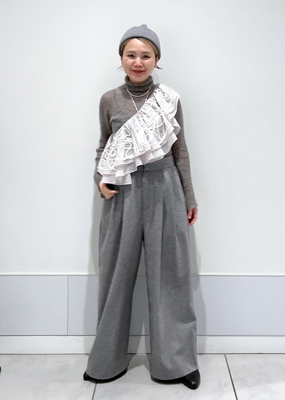 ブラック系のブーツ、グレー系のニット/セーター、ベージュ系のストール/ショールを着用したレディースの冬コーディネートの2枚目の写真