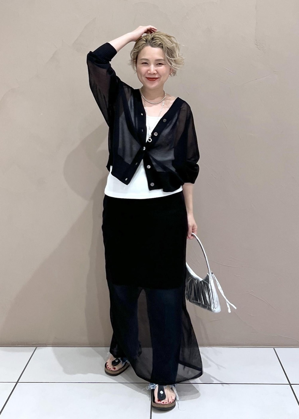 ホワイト系のタンクトップ、ブラック系のカーディガン/ボレロ、ブルー系のデニムパンツを着用したレディースの夏コーディネートの2枚目の写真