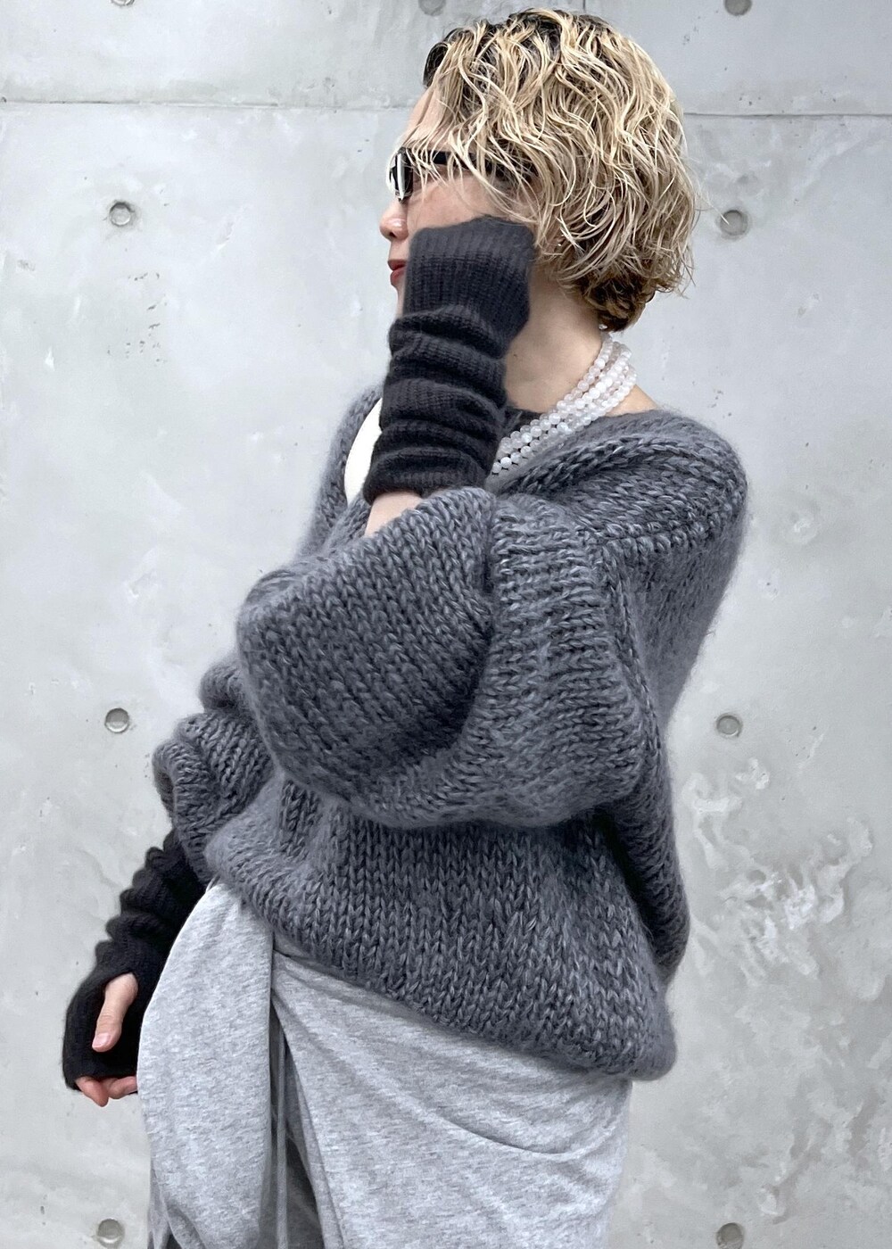 グレー系のニット/セーター、ホワイト系のボディバッグ/ウエストポーチ、グレー系の手袋を着用したレディースの秋コーディネートの6枚目の写真