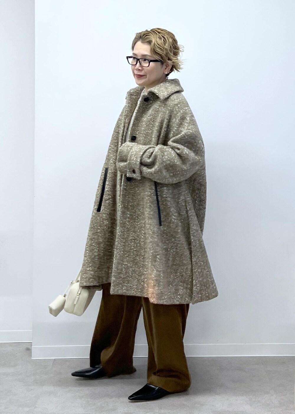 ホワイト系のスウェット、ベージュ系のステンカラーコート、ブラウン系のその他パンツを着用したレディースの秋コーディネートの3枚目の写真