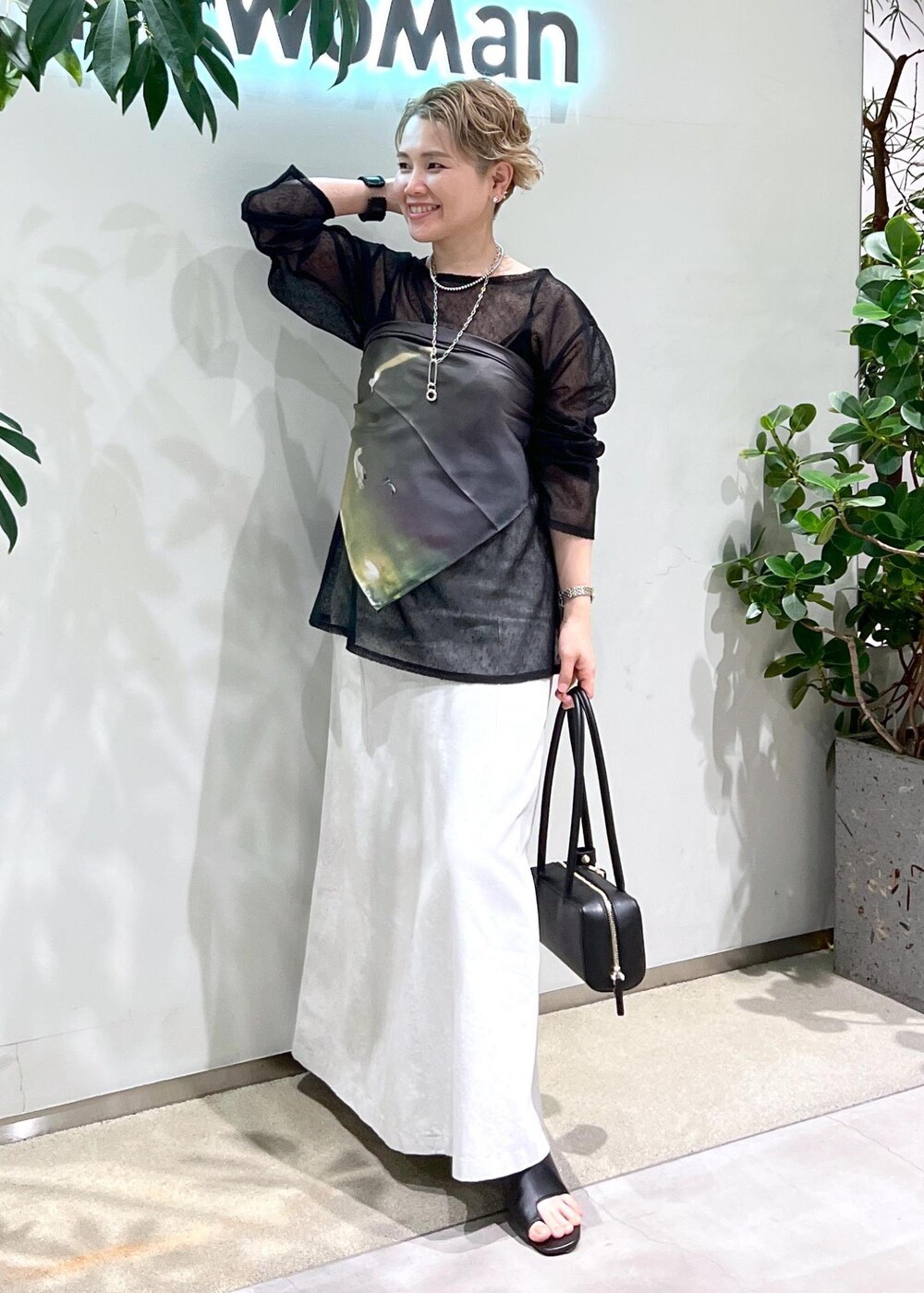 ホワイト系のスカート、ブラック系のサンダル、ブラック系のショルダーバッグを着用したレディースの夏コーディネートの2枚目の写真