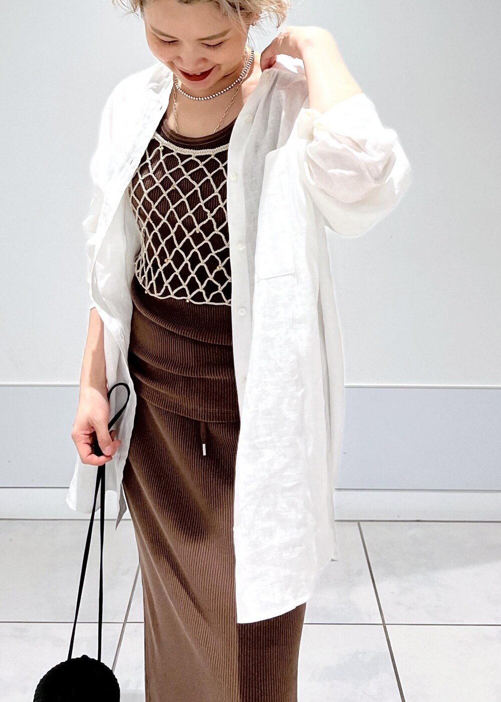 ブラック系のショルダーバッグ、ベージュ系のキャミソール、ブラウン系のタンクトップを着用したレディースの夏コーディネートの6枚目の写真