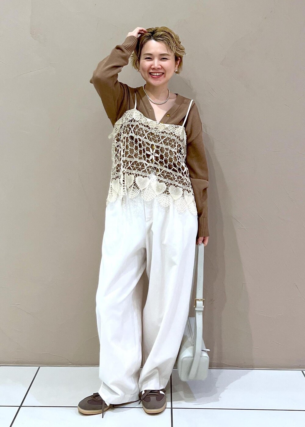 グレー系のショルダーバッグ、ホワイト系のその他パンツ、イエロー系のカーディガン/ボレロを着用したレディースの春コーディネートの2枚目の写真