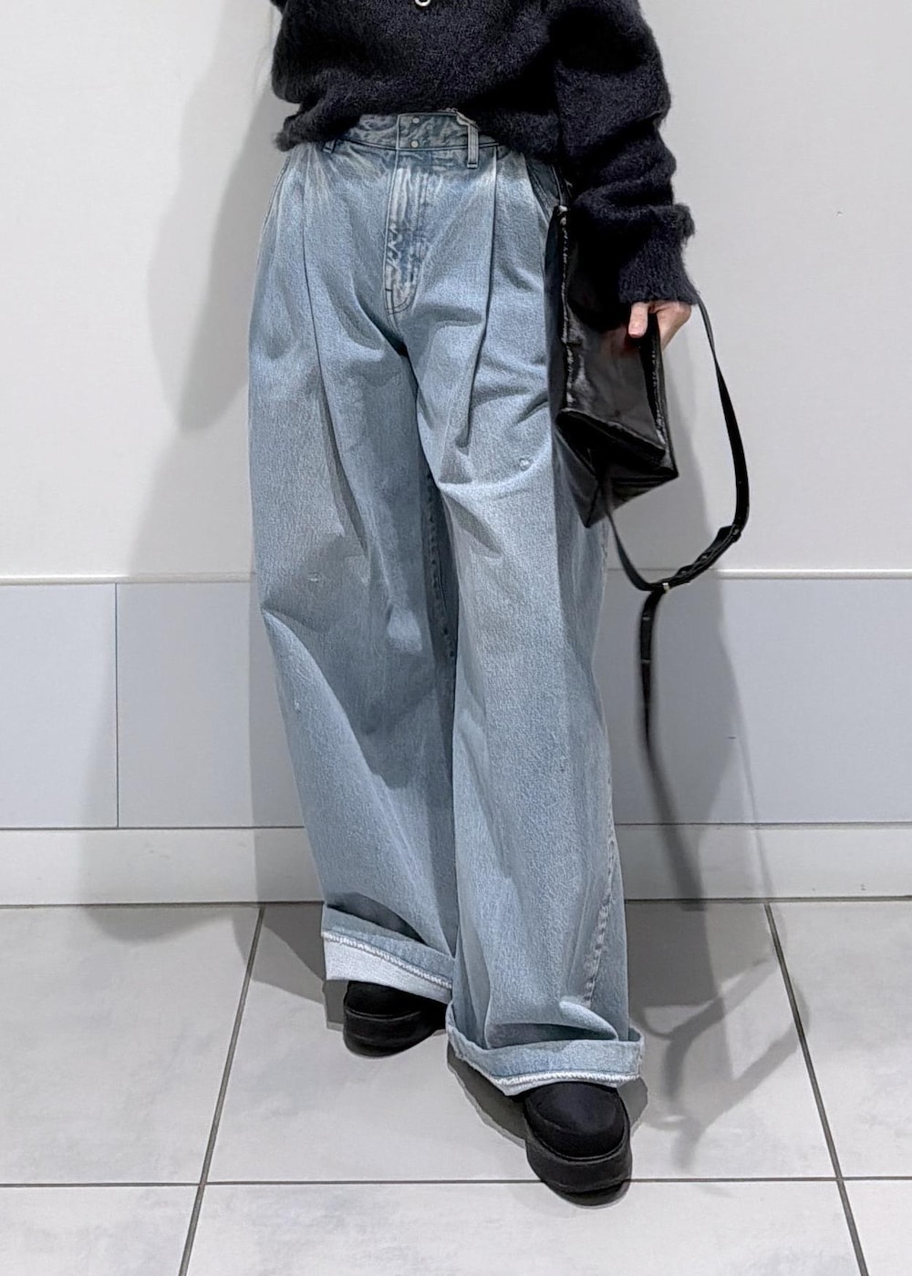 ブラック系のショルダーバッグ、ブラック系のブーツ、ブルー系のデニムパンツを着用したレディースの秋コーディネートの8枚目の写真