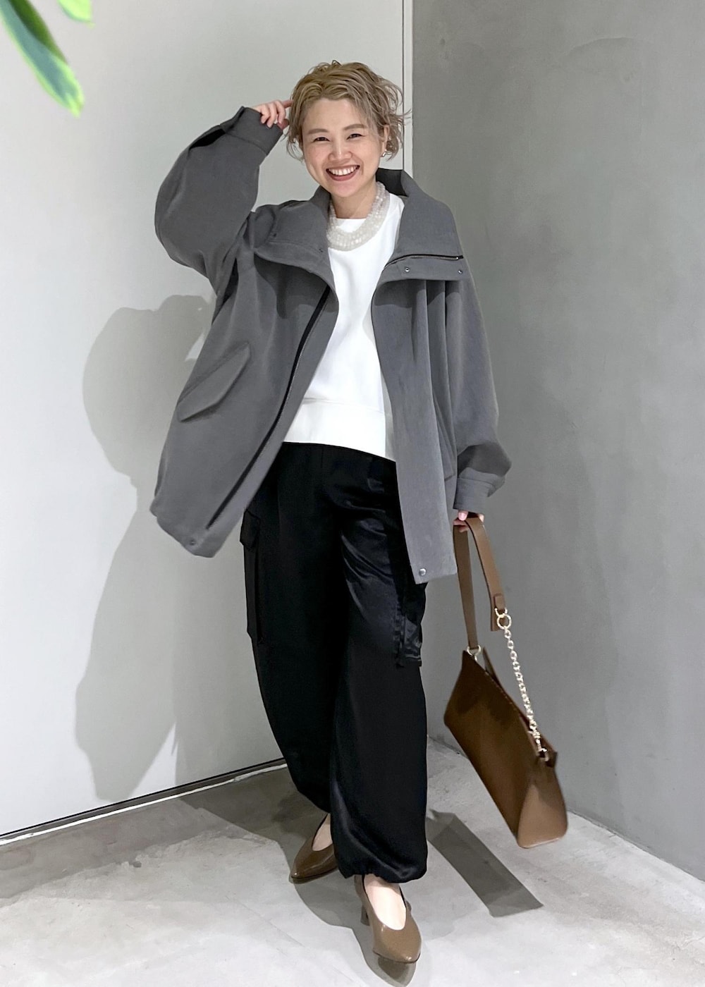 ブラウン系のショルダーバッグ、ブラック系のカーゴパンツ、ホワイト系のスウェットを着用したレディースの秋コーディネートの4枚目の写真