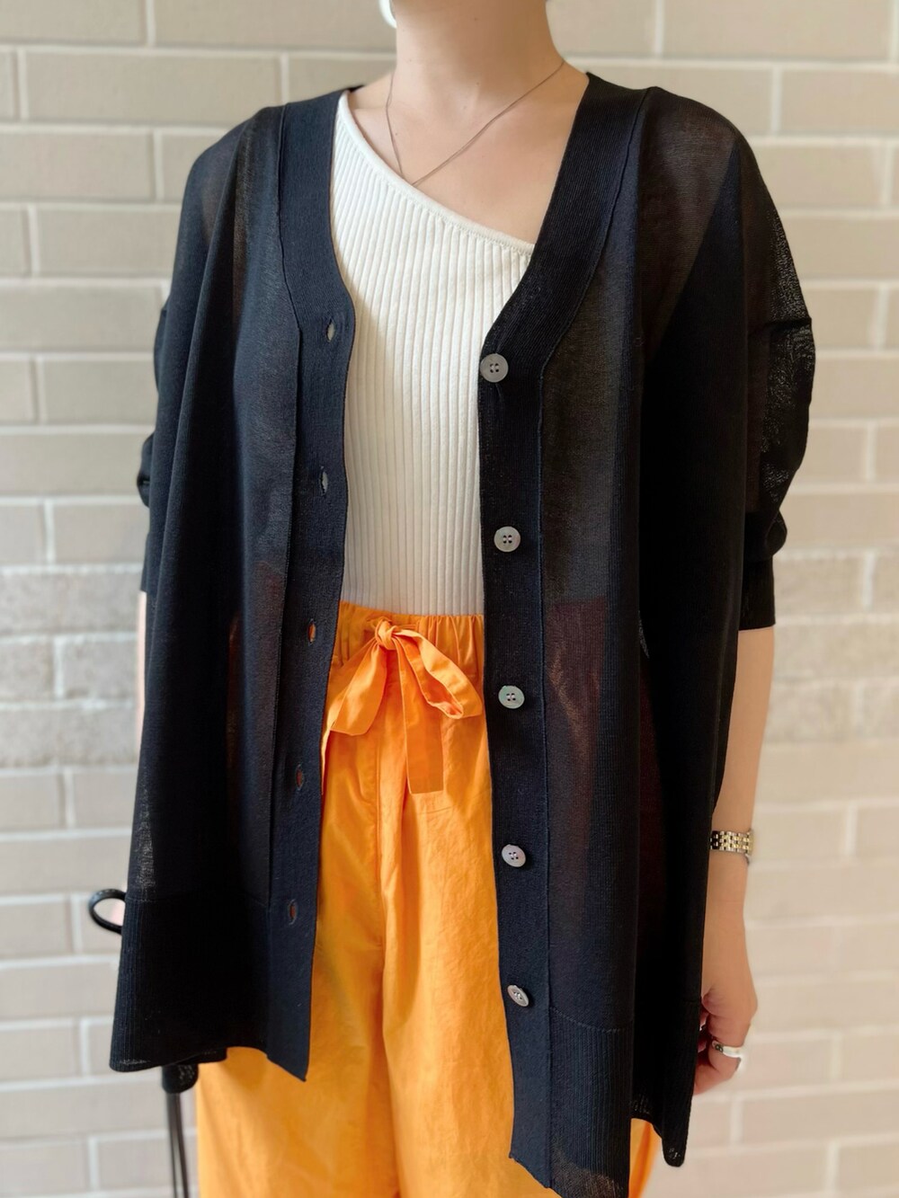 ブラック系のカーディガン/ボレロ、オレンジ系のパンツ、ブラック系のショルダーバッグを着用したレディースの夏コーディネートの4枚目の写真