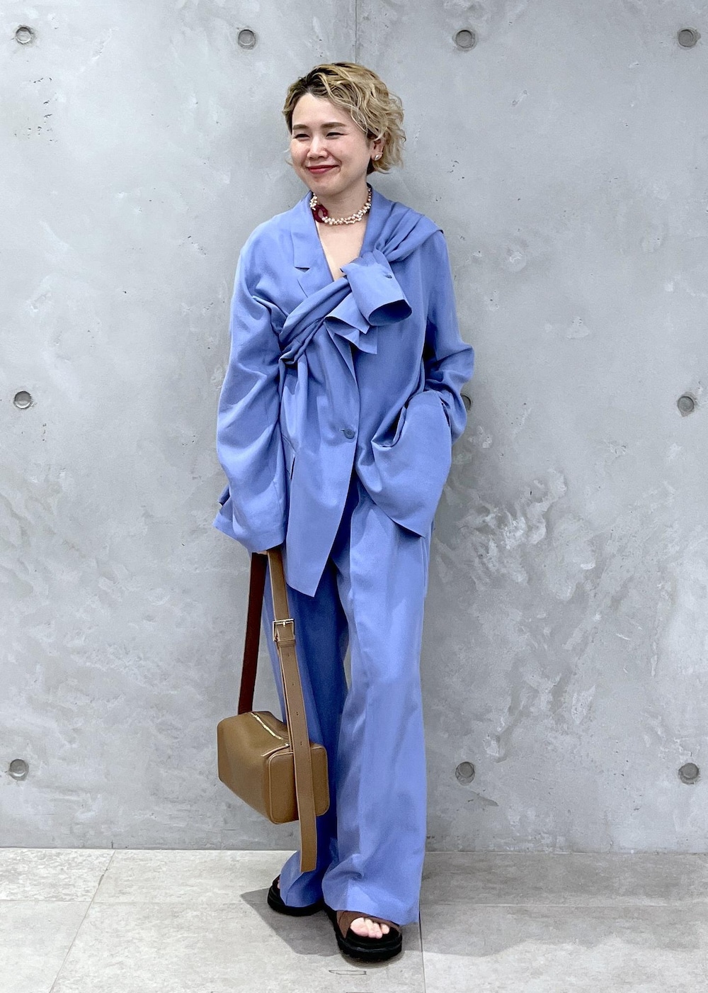 ブラウン系のショルダーバッグ、ブラウン系のサンダル、ブルー系のテーラードジャケットを着用したレディースの冬コーディネートの4枚目の写真