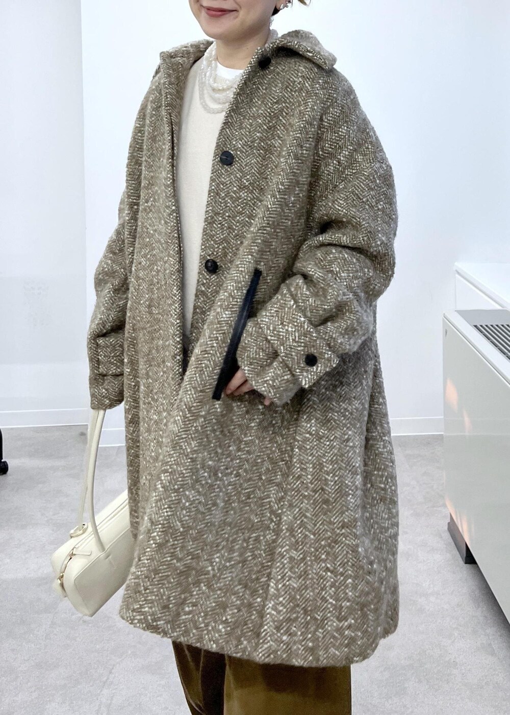 ホワイト系のスウェット、ベージュ系のステンカラーコート、ブラウン系のその他パンツを着用したレディースの秋コーディネートの7枚目の写真